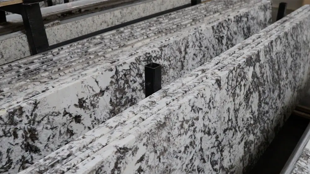 A stack of White Orion granite countertop slabs showing the white base with soft gray veining