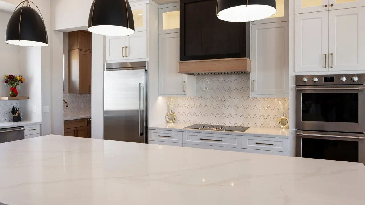 A custom range hood above a cooktop, with Calacatta Elysio quartz countertops and backsplash