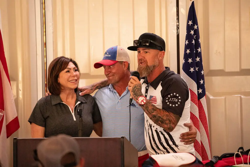 Tournament awards ceremony — a Folds of Honor representative addresses attendees at the podium, flanked by American flags